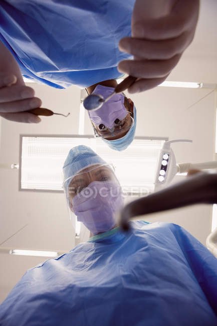 Vista a basso angolo dei dentisti che tengono strumenti dentali presso la clinica dentistica — Foto stock
