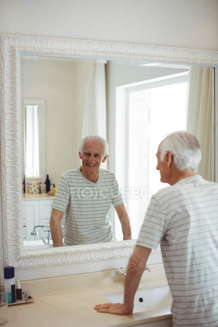 Uomo anziano guardando specchio in bagno — Foto stock