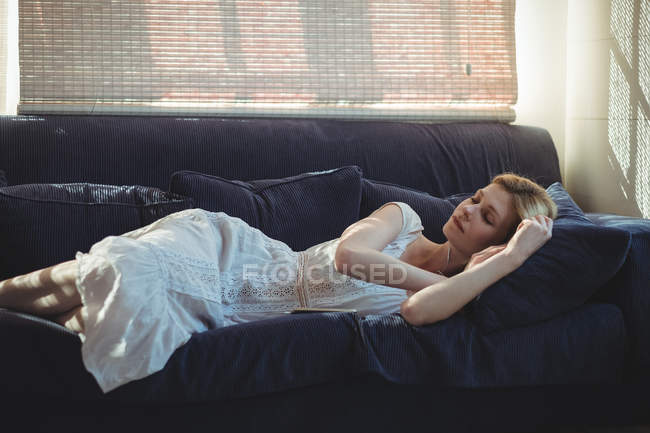 Красива жінка розслабляється на дивані у вітальні вдома — стокове фото