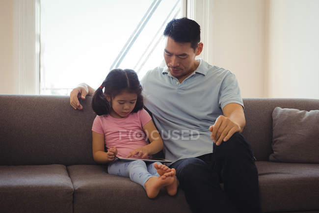 Pai e filha usando tablet digital na sala de estar em casa — Fotografia de Stock
