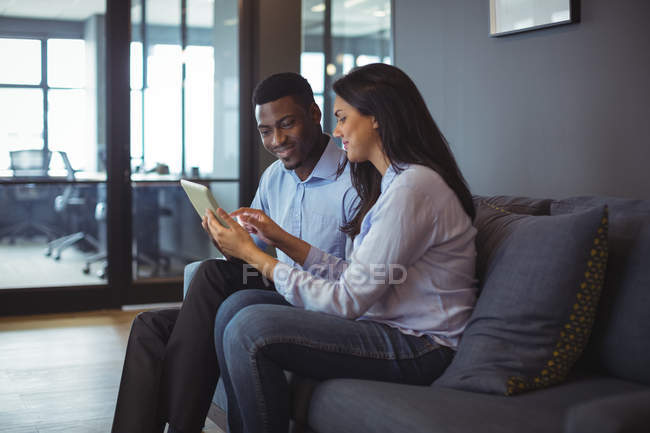 Businessman and a colleague discussing over digital tablet in office — Stock Photo