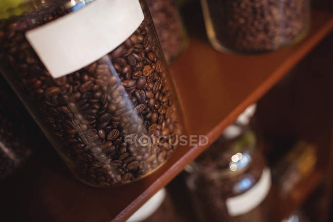 Gros plan du pot de grains de café disposés sur l'étagère dans le magasin — Photo de stock