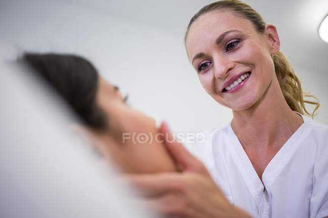 Врач, осматривающий пациентку для косметического лечения в клинике — стоковое фото