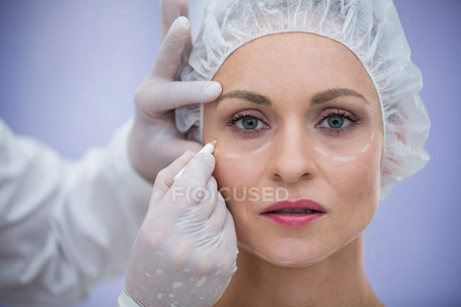 Nahaufnahme eines Arztes, der das Gesicht einer Patientin für kosmetische Behandlungen markiert — Stockfoto