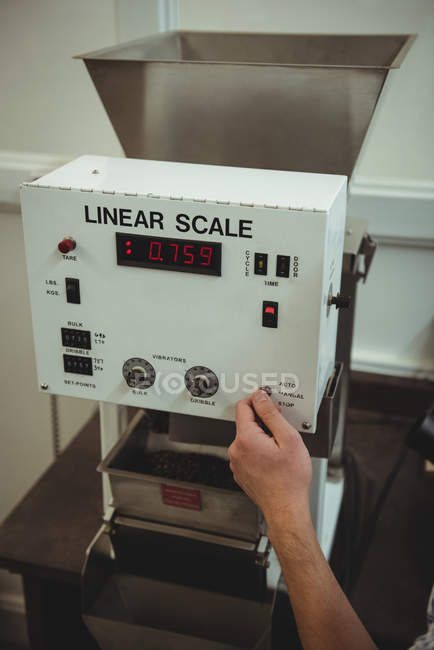Hand of man using a coffee weighing machine — Stock Photo