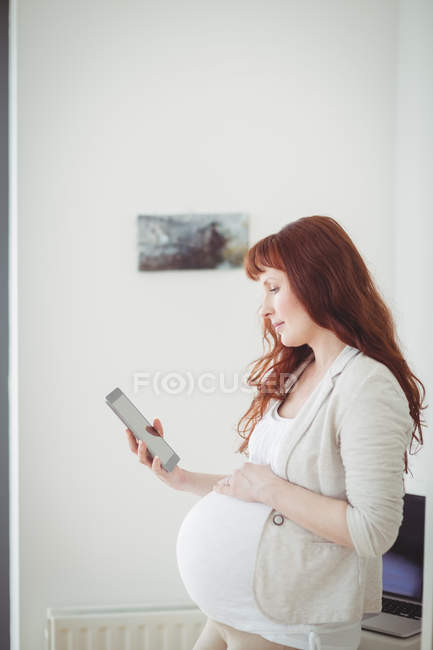 Donna incinta che utilizza tablet digitale in sala studio a casa — Foto stock