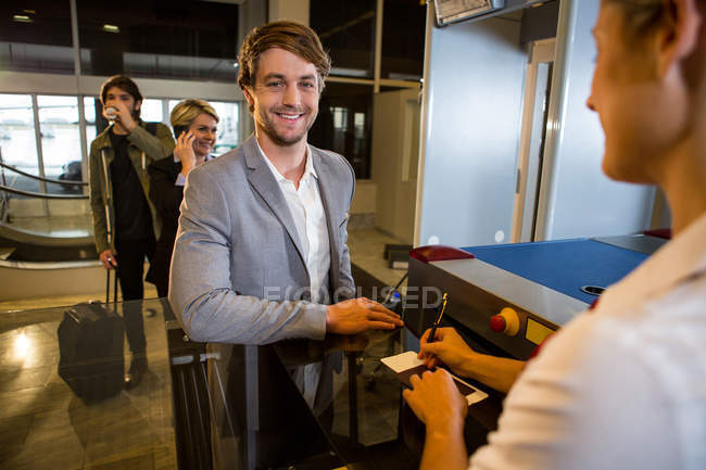 Businessman in queue receiving passport and boarding pass at airport terminal — Stock Photo