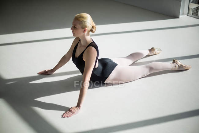 Bailarina esticando-se no chão no estúdio — Fotografia de Stock