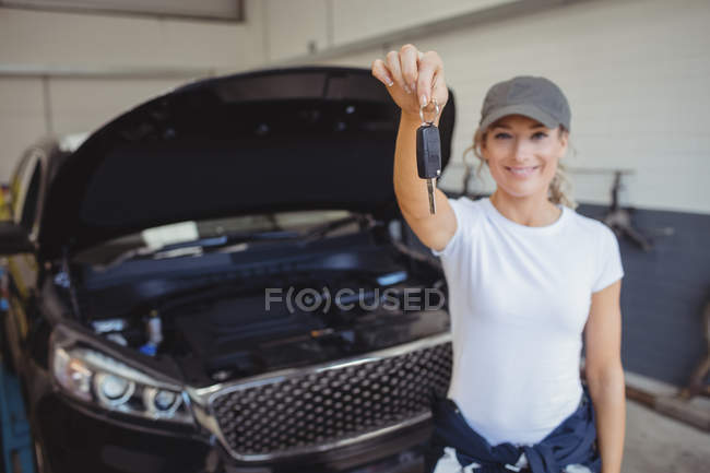 Retrato do mecânico feminino na garagem segurando a chave do carro — Fotografia de Stock