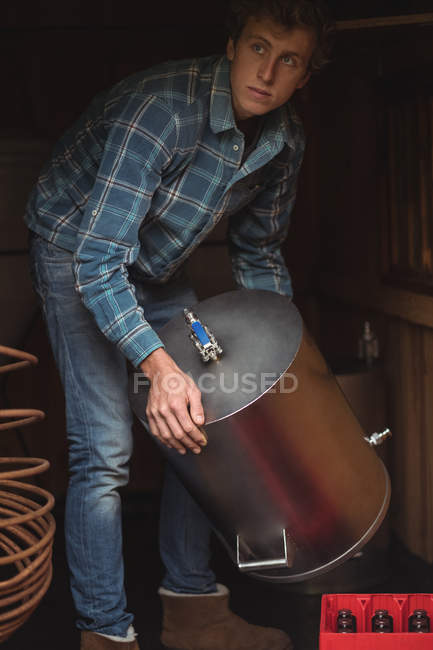 Man lifting wort to make beer at home brewery — Stock Photo