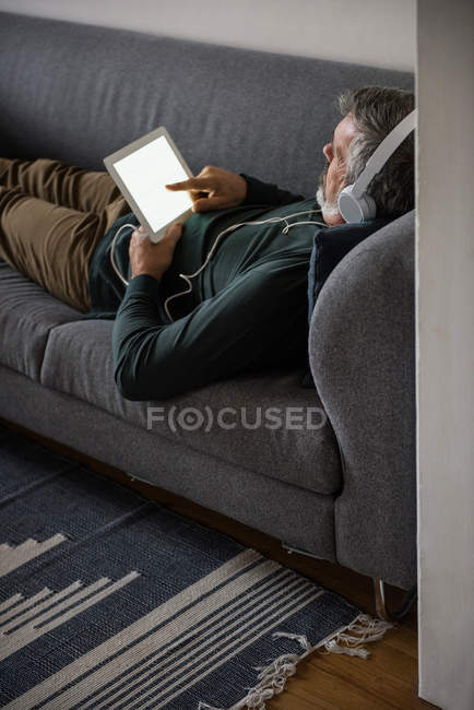 Людина прослуховування музики на цифровий планшетний вдома — стокове фото