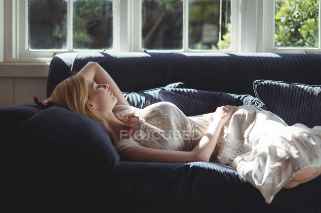 Красива жінка розслабляючий на дивані у вітальні на дому — стокове фото