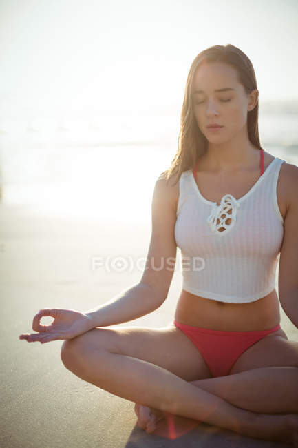 Красива жінка, що виконує йогу на пляжі в сонячний день — стокове фото