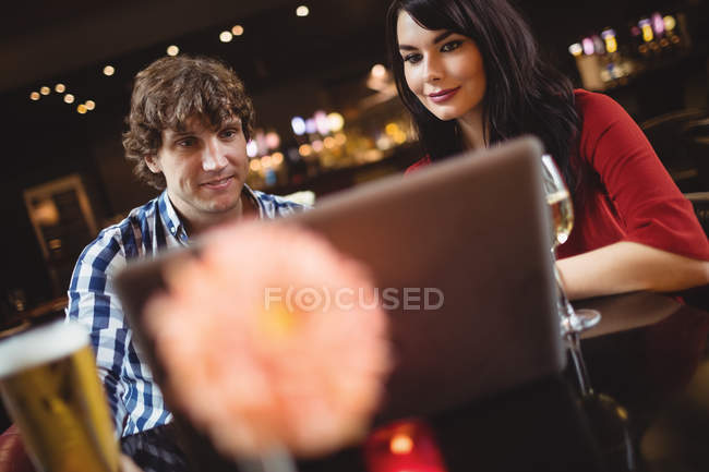 Пара с ноутбуком во время напитков в баре — стоковое фото