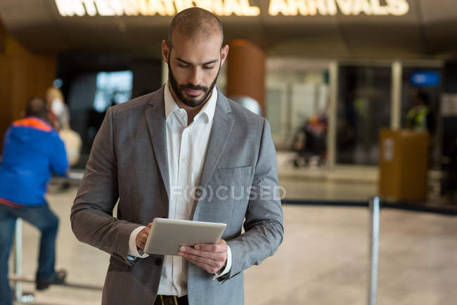 Homme d'affaires utilisant une tablette numérique dans la salle d'attente au terminal de l'aéroport — Photo de stock