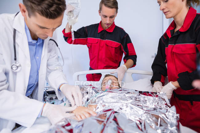 Doctor and paramedics examining a patient in emergency room at hospital — Stock Photo