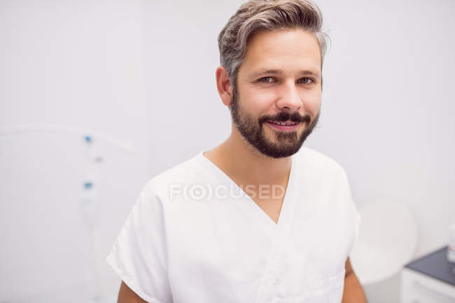 Portrait of mid adult male dentist standing in clinic — Stock Photo