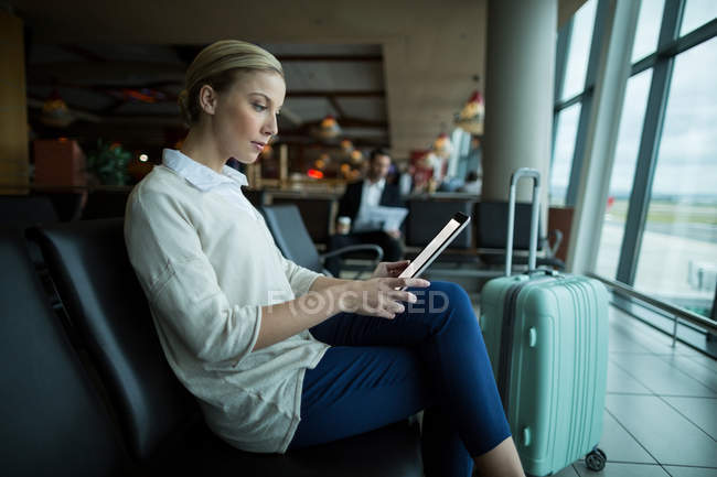 Жінка-комісар, що використовує цифровий планшет в зоні очікування в аеропорту — стокове фото