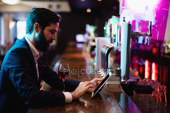 Бізнесмен використовує цифровий планшет з келихом вина на лічильнику в барі — стокове фото