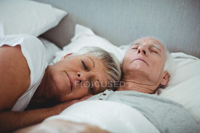 Casal sênior dormindo na cama no quarto — Fotografia de Stock