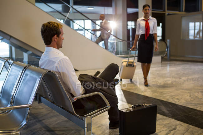 Empresario usando el teléfono mientras camina en la terminal del aeropuerto - foto de stock