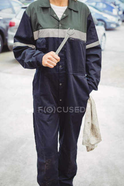 Mid-section of female mechanic holding wrench in repair garage — Stock Photo