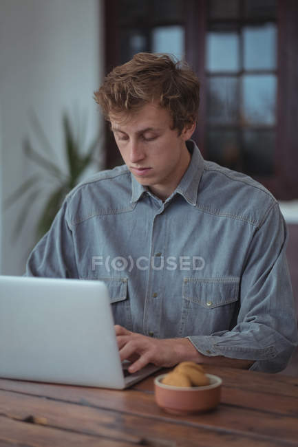 Mann sitzt am Tisch und arbeitet am Laptop — Stockfoto