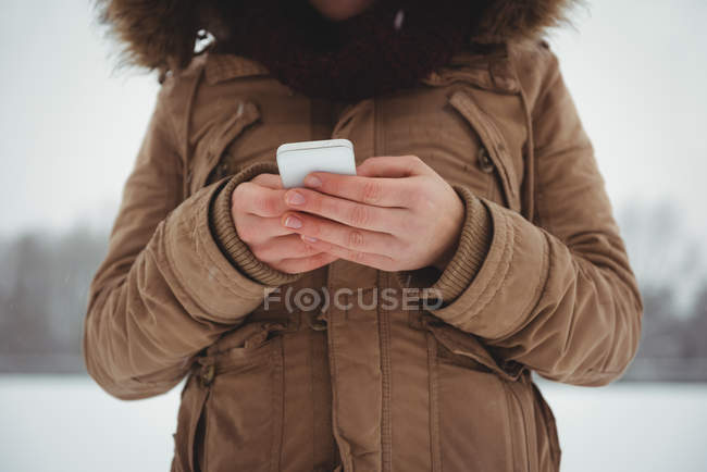 Frau in Pelzjacke benutzt im Winter Handy — Stockfoto