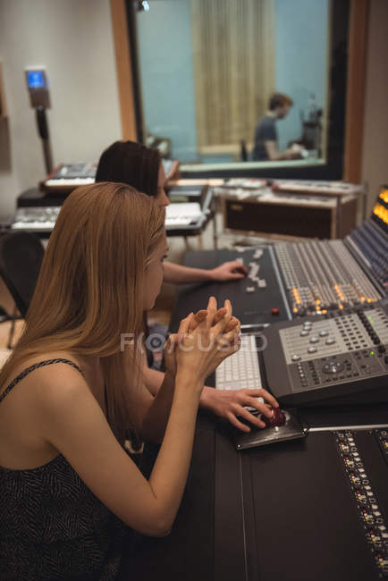 Audio engineer sitting with hands clasped near sound mixer in recording studio — Stock Photo