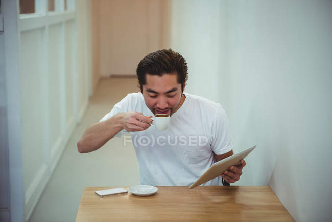 Homem usando tablet digital enquanto toma café no café — Fotografia de Stock