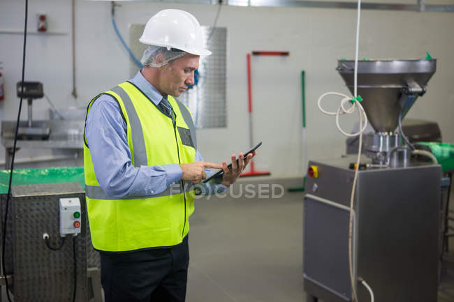 Technicien attentif utilisant une tablette numérique à l'usine de viande — Photo de stock