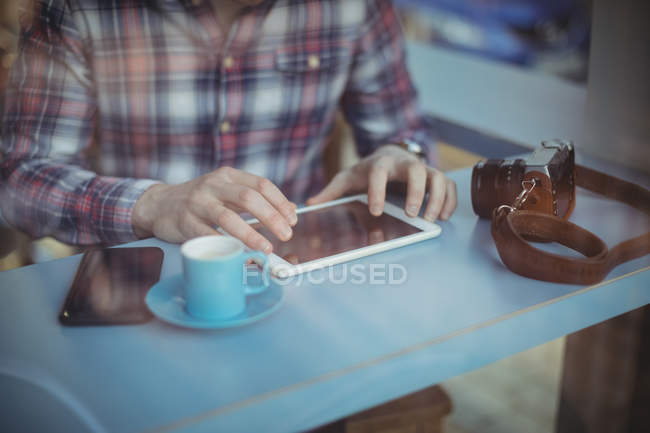 Mid-section of man using digital tablet in cafeteria — Stock Photo