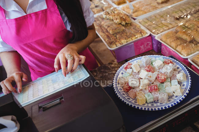 Mid section of female shopkeeper using cash register in shop — Stock Photo