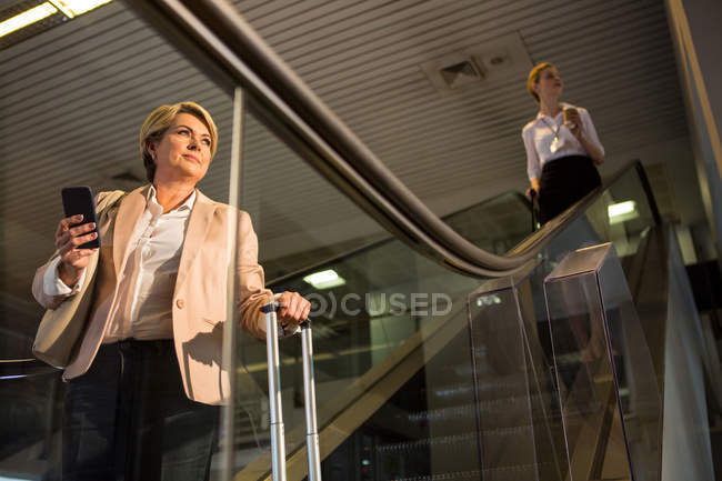 Female passenger coming down from the escalator in the airport terminal — Stock Photo