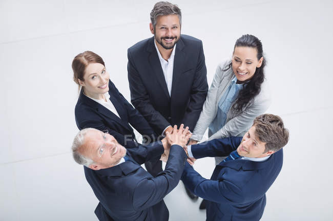 Retrato de gente de negocios apilándose las manos en la oficina - foto de stock