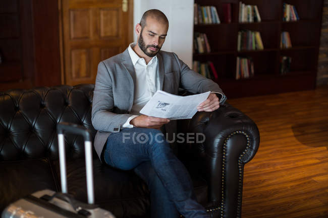 Businessman reading newspaper in waiting area at airport terminal — Stock Photo