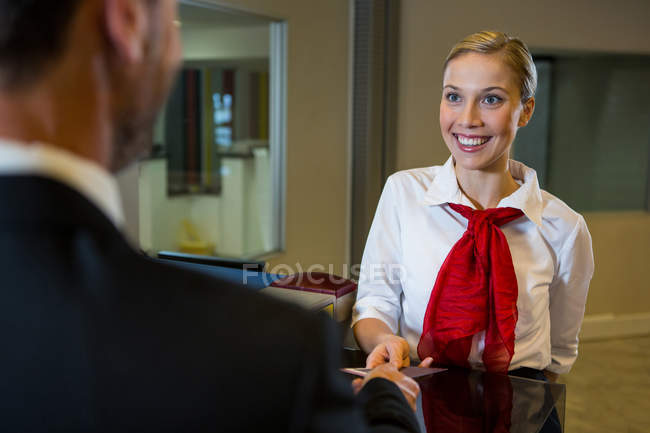 Жіночий персонал, який дає посадковий талон бізнесмену на чеку за столом — стокове фото