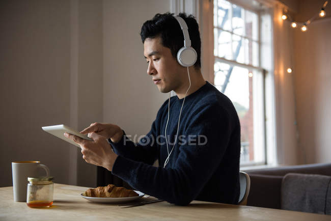 Hombre escuchando música en tableta digital en casa - foto de stock