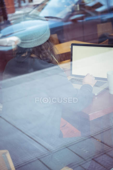 Woman in winter clothing using laptop in restaurant — Stock Photo