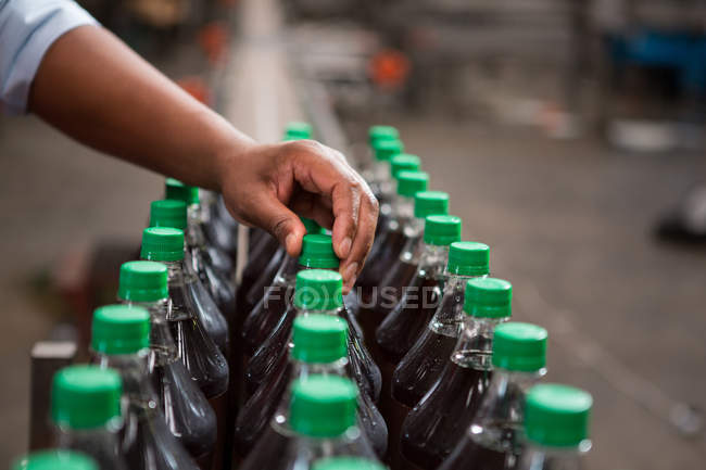 Cropped hand of worker inspecting bottles in juice factory — Stock Photo