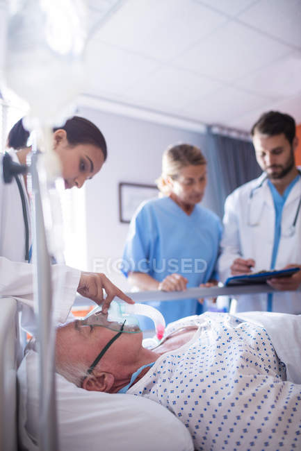 Female doctor putting oxygen mask on patient face in the hospital — Stock Photo
