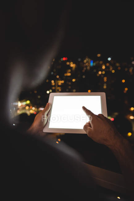 Вид сзади на человека, использующего цифровой планшет на балконе ночью — стоковое фото