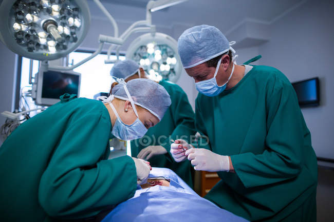 Grupo de cirujanos realizando operación en quirófano del hospital - foto de stock