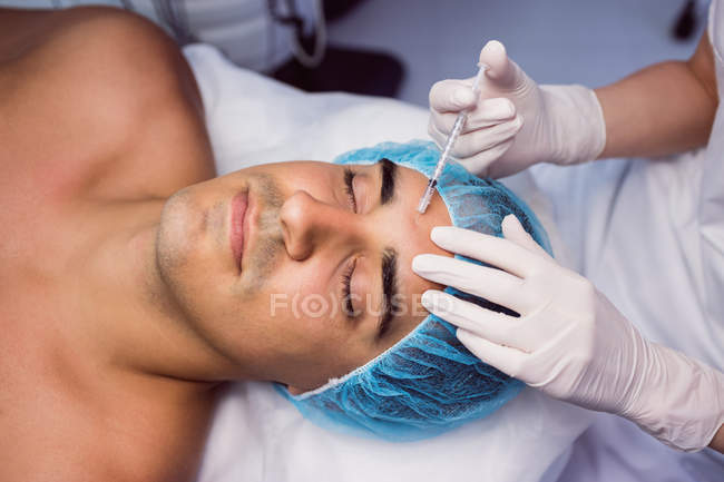 Чоловік отримує ін'єкцію ботоксу на лобі в клініці — стокове фото