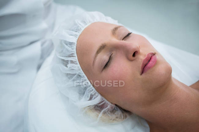 Patient couché sur le lit tout en recevant un traitement cosmétique en clinique — Photo de stock