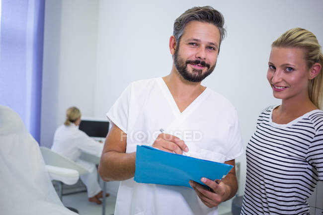 Retrato del médico discutiendo informe con paciente en clínica - foto de stock