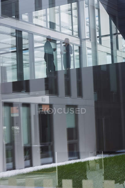 Geschäftsfrau interagiert mit einem Kollegen im Flur eines Bürogebäudes — Stockfoto