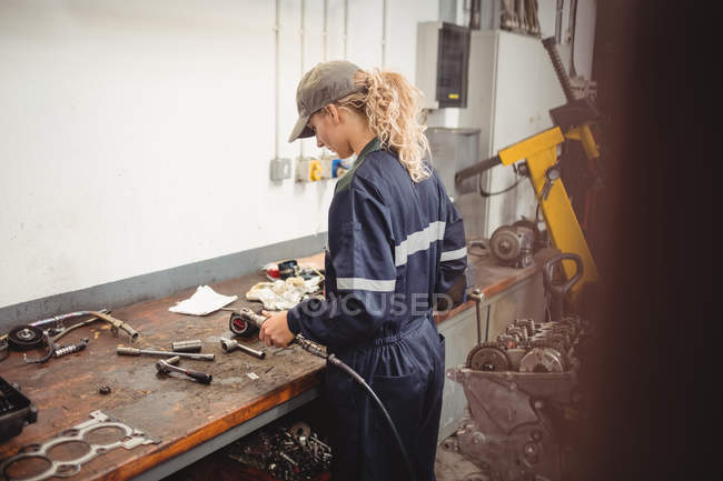 Feminino mecânico verificando um carro peças na garagem de reparação — Fotografia de Stock