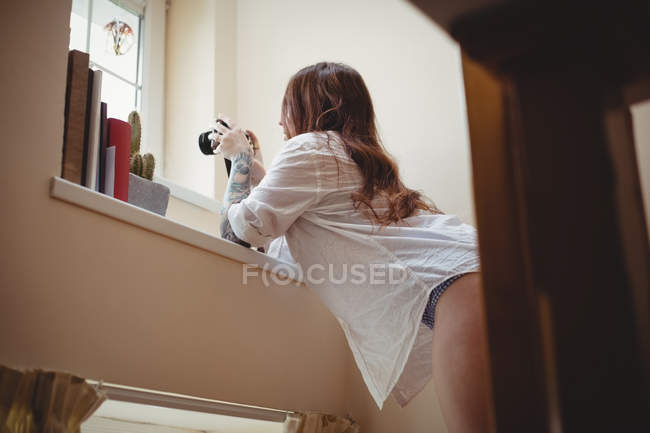 Femme prenant des photos sur appareil photo numérique à la maison — Photo de stock