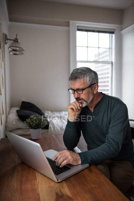 Homme utilisant un ordinateur portable dans le salon à la maison — Photo de stock